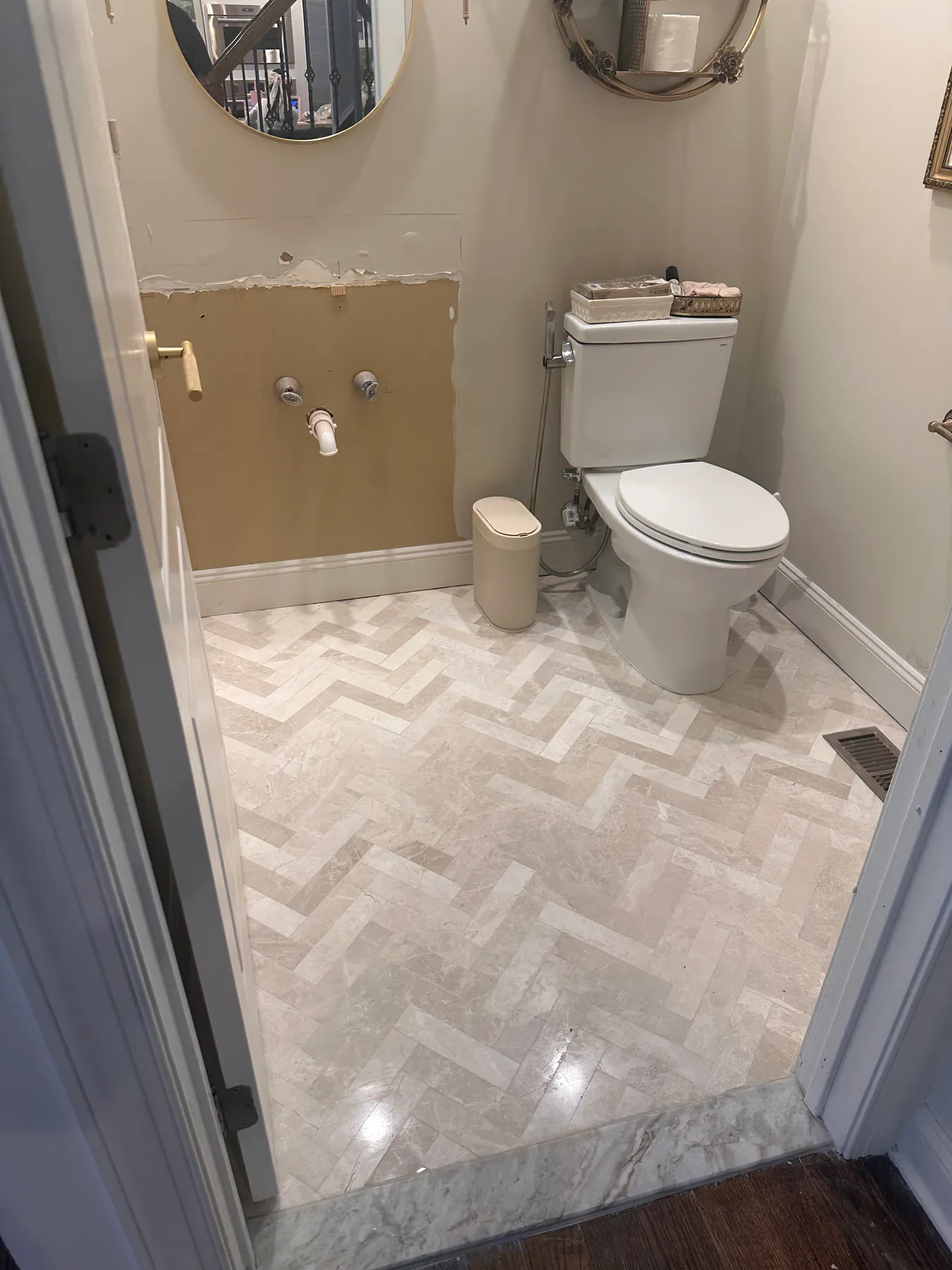Herringbone marble tile floor in a powder room remodel, cut clean to the baseboard on every side