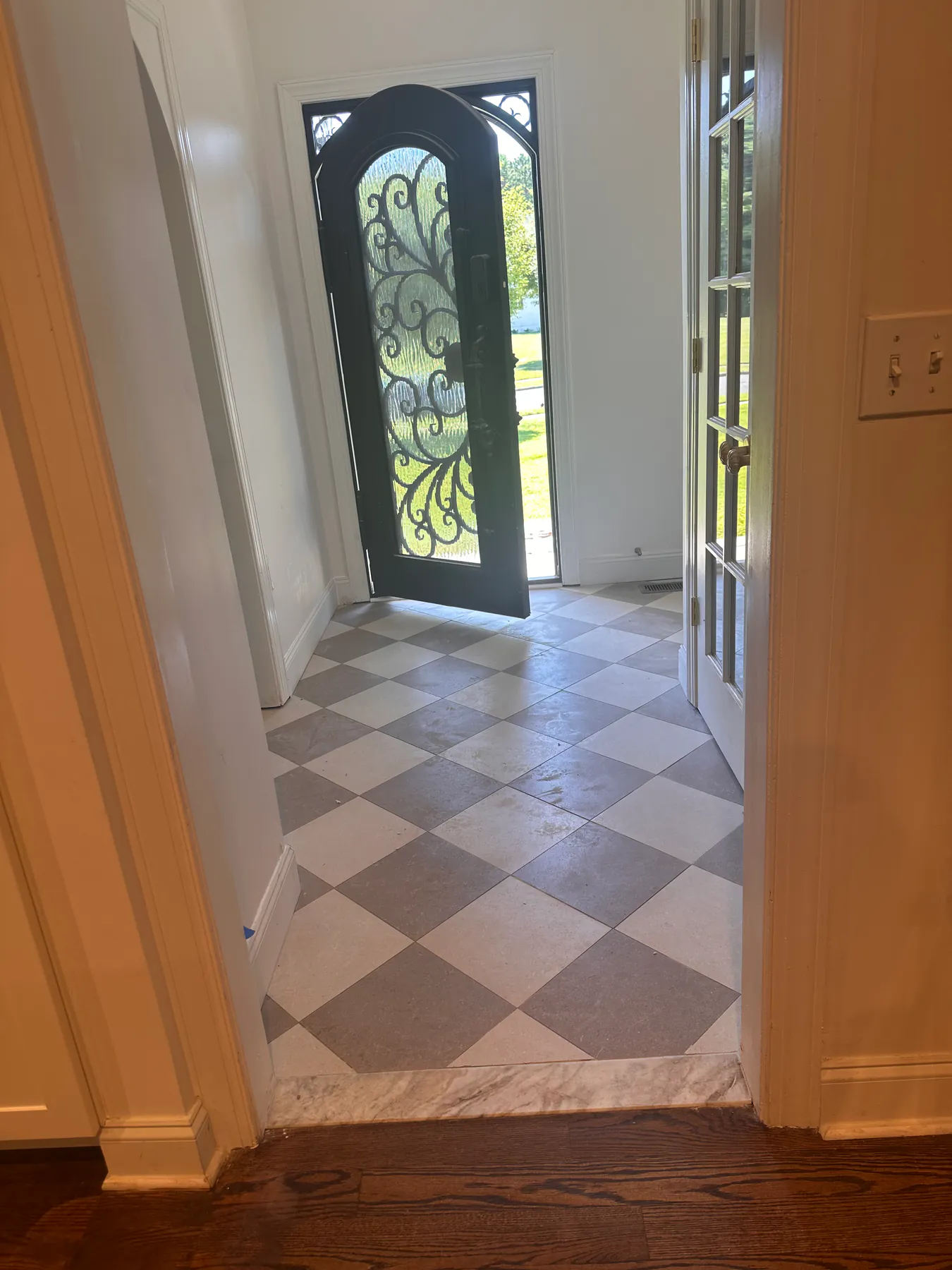 Checkerboard tile meeting hardwood flooring at a level transition in a hallway doorway