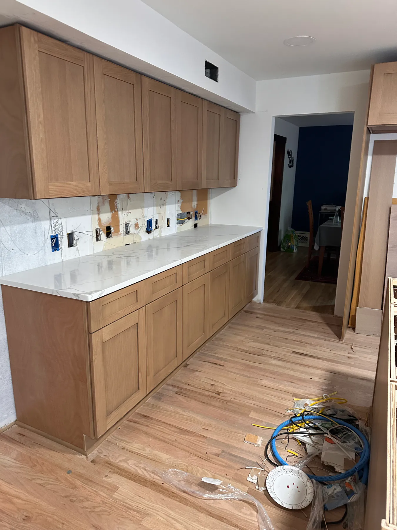 Galley run of white oak kitchen cabinets under a quartz counter, set on red oak hardwood flooring