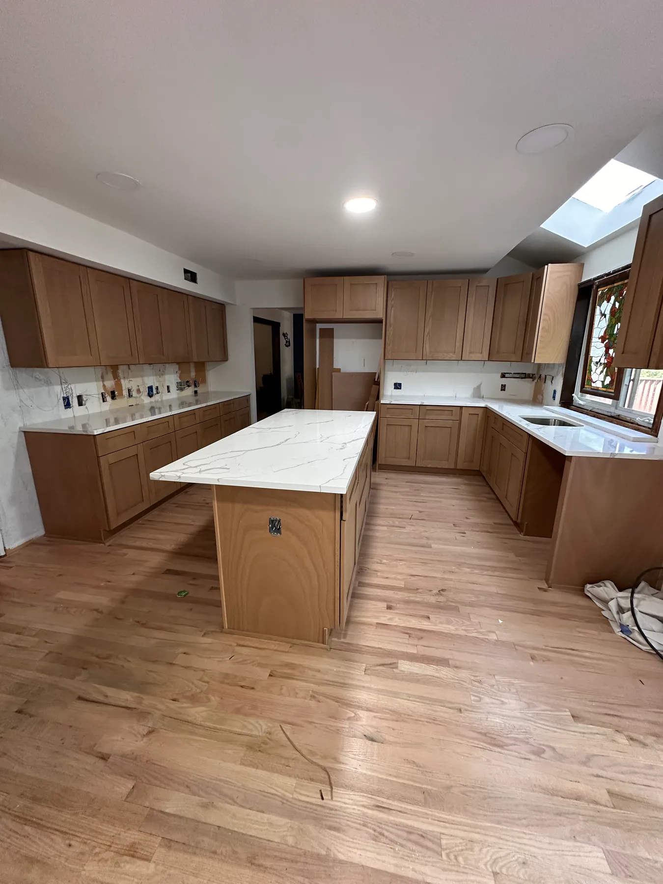 Open-plan kitchen with a long calacatta quartz island and hardwood flooring running to the far wall