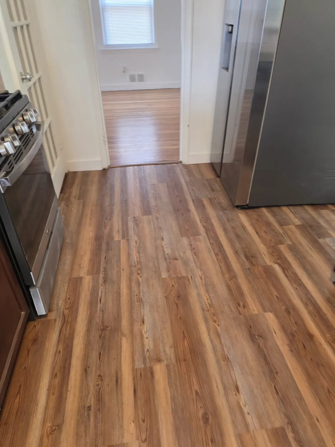 Rustic oak luxury vinyl plank flooring running through a kitchen and into the next room